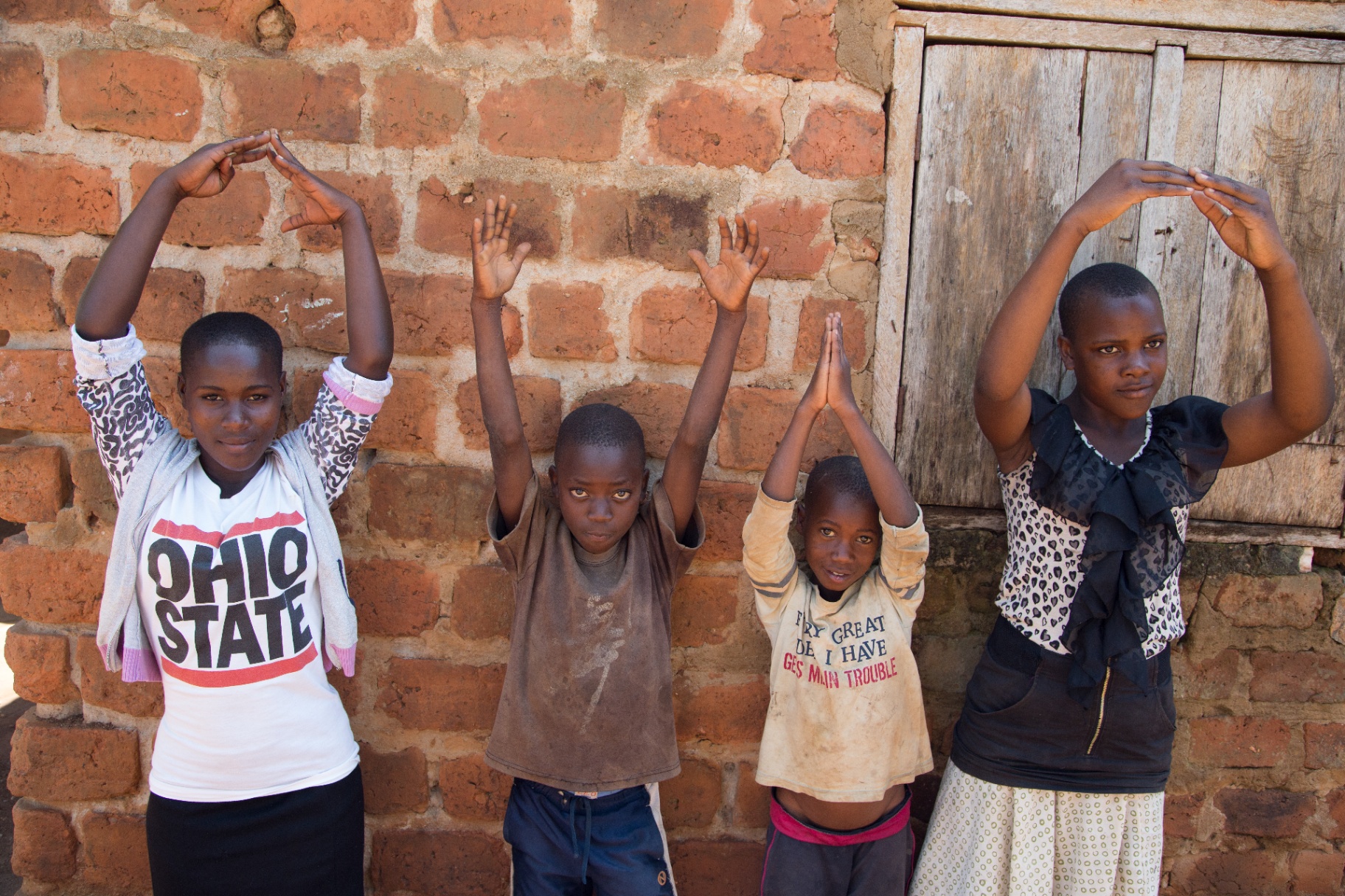 Ugandan children raise their hands